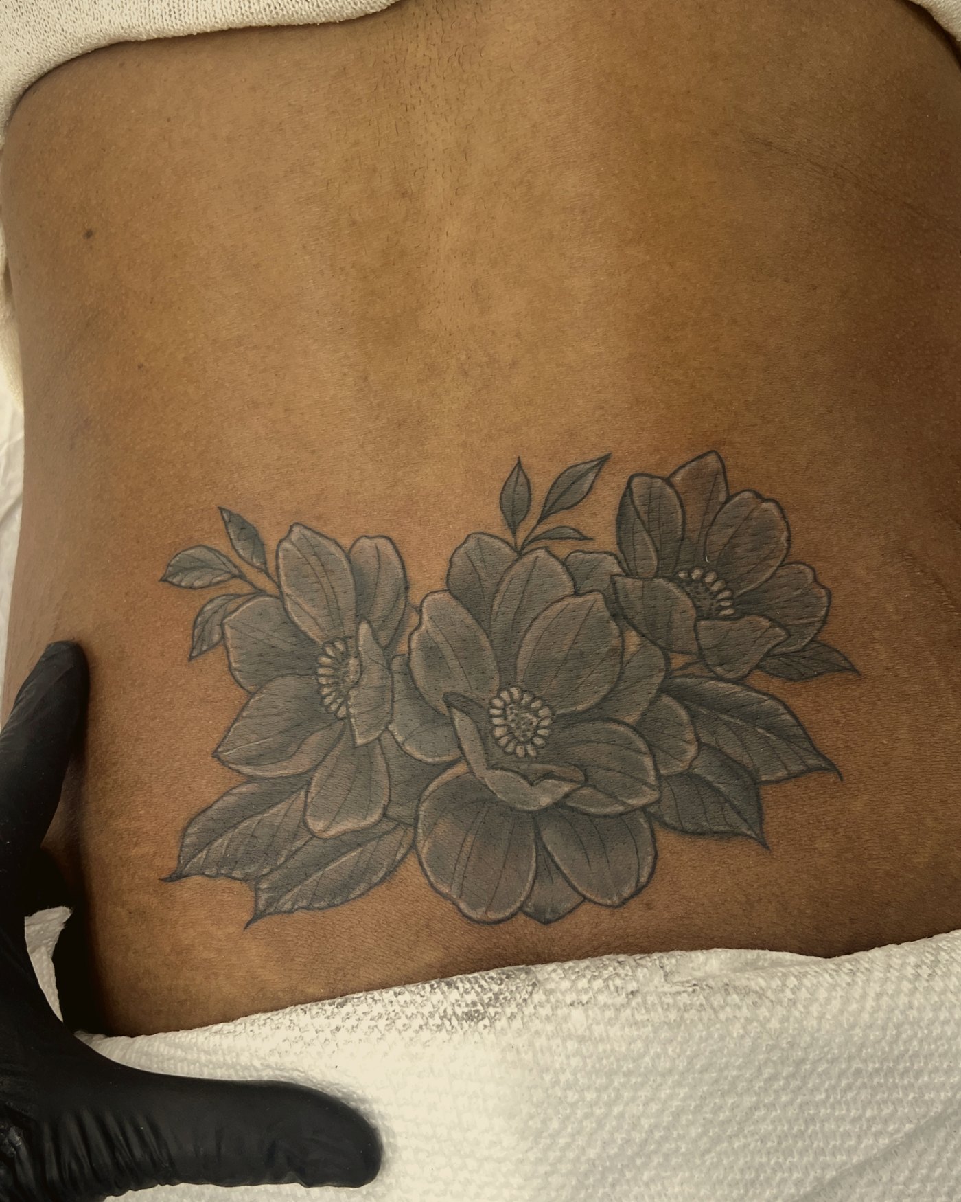 Soft black & grey florals across the lower back — by Paul Aroca, Crown Ink Studio Brooklyn